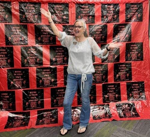 Image of Jen Hardy in front of a banner that says Boom In Your Face Podcast.