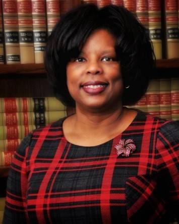 Judge Stephanie Boyd in a red and black plaid shirt in front of bookshelves